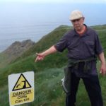 Don pointing at a warning sign at the Cliffs of Moher