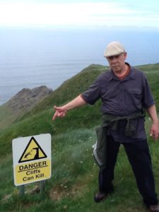 Don pointing at a warning sign at the Cliffs of Moher